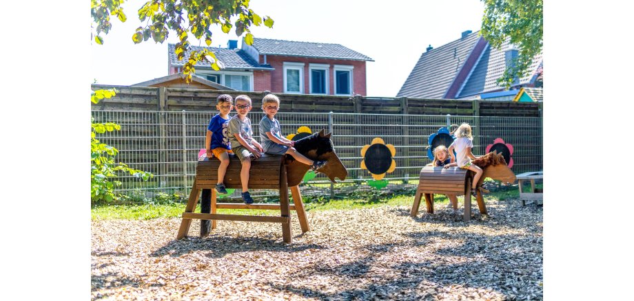 Kinder im Kindergarten auf Holzpferd