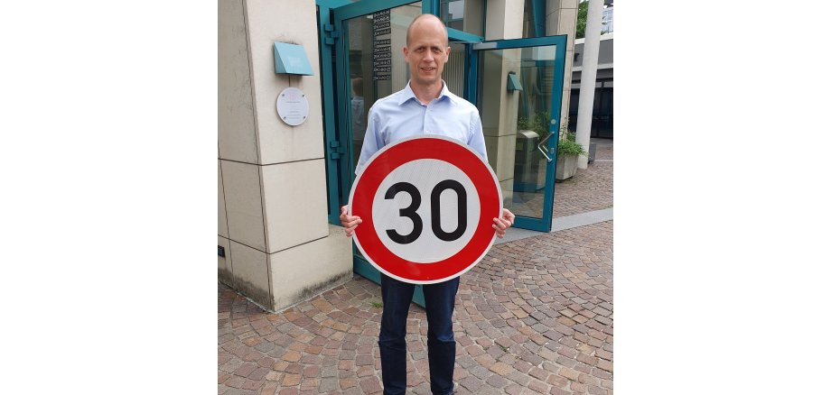 Bürgermeister Kai Louis mit einem Verkehrsschild Tempo 30