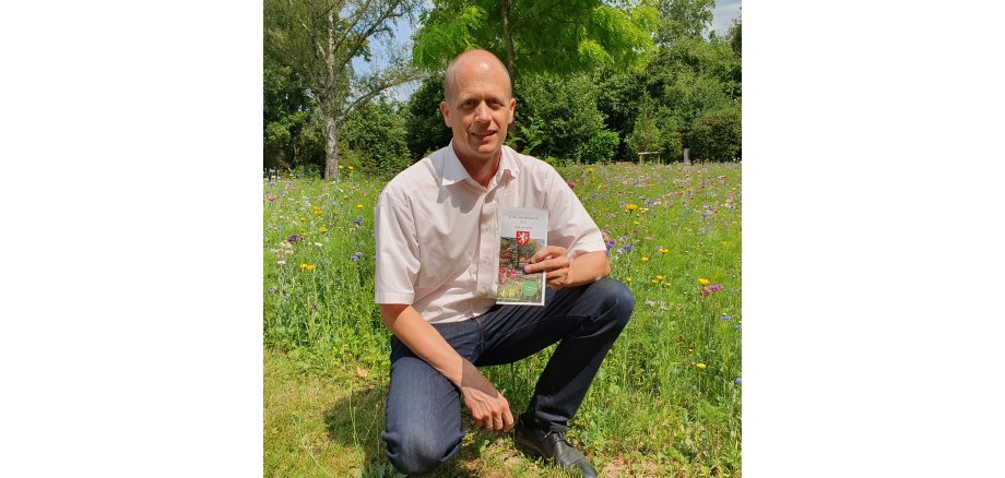 Bürgermeister Kai Louis mit dem aktuellen Flyer zur Teilnahme am Gartenwettbewerb 2023