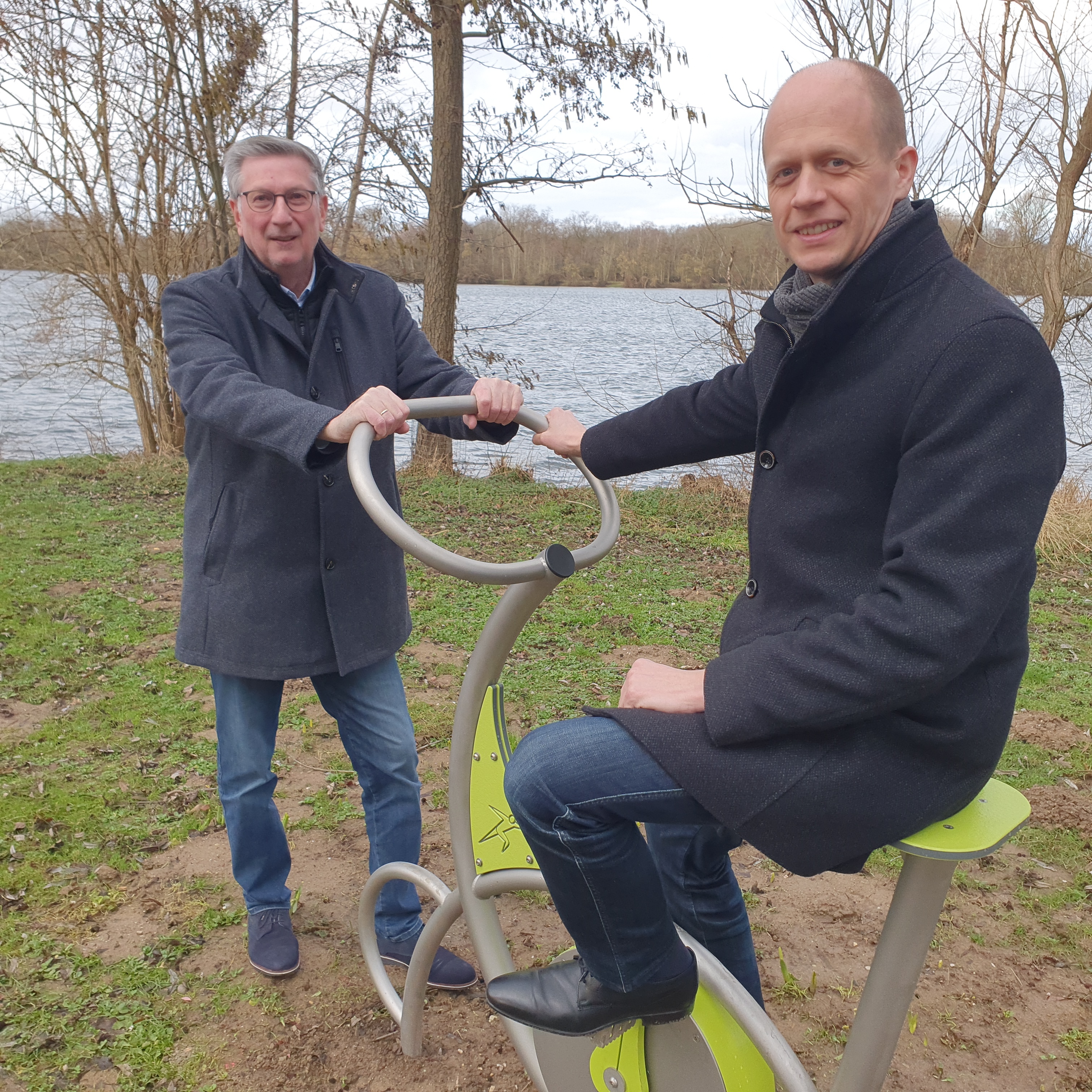 Bürgermeister Kai Louis und Ortsvorsteher Siggi Jansen testen die neuen Sportgeräte am Lago Laprello