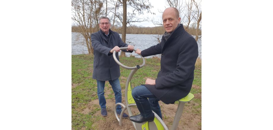 Bürgermeister Kai Louis und Ortsvorsteher Siggi Jansen testen die neuen Sportgeräte am Lago Laprello